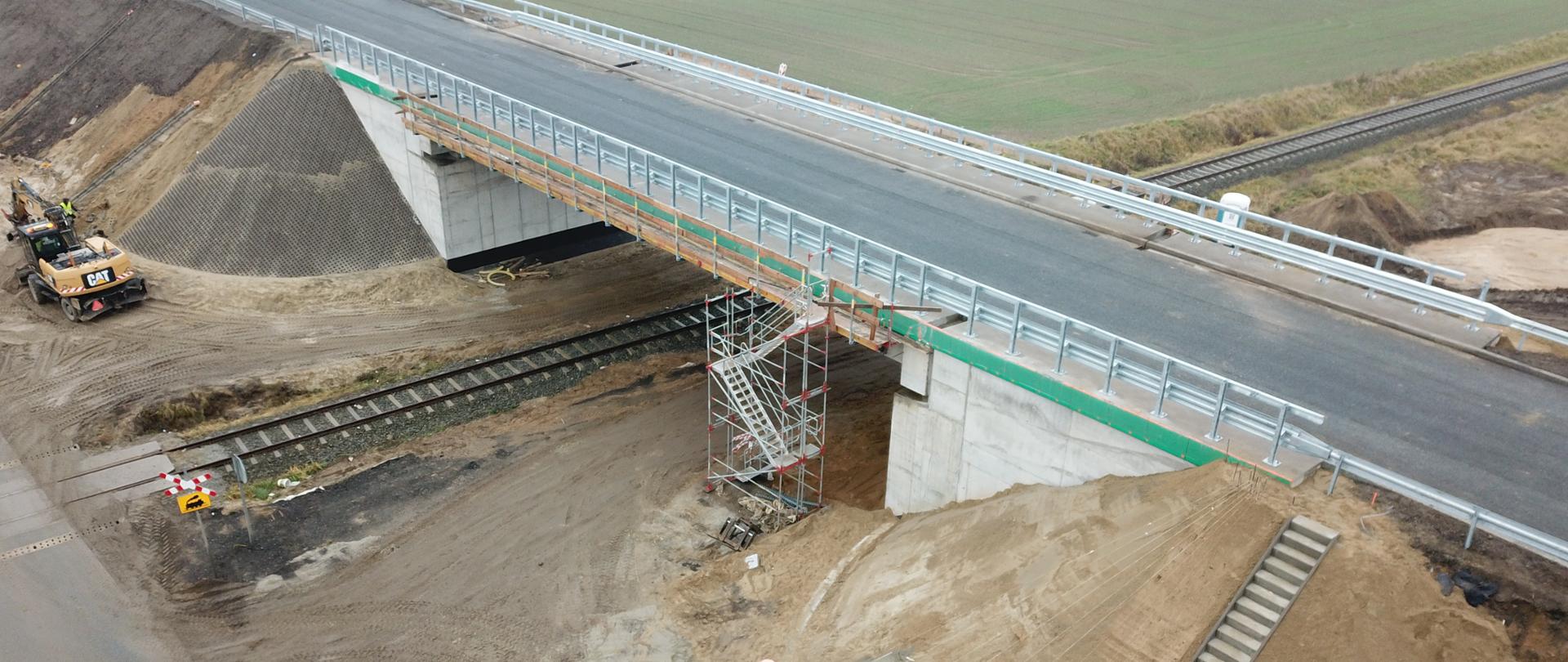 Budowa wiaduktu na trasie Krapkowice - Rogów Opolski w ciągu DK45. Wiadukt przed obciążeniami próbnymi i pozwoleniem na użytkowanie. W tle prace budowlane pod wiaduktem oraz fragment drogi tymczasowej wybudowanej na czas prowadzonych prac.