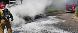 Strażacy gaszą pianą palący się samochód dostawczy