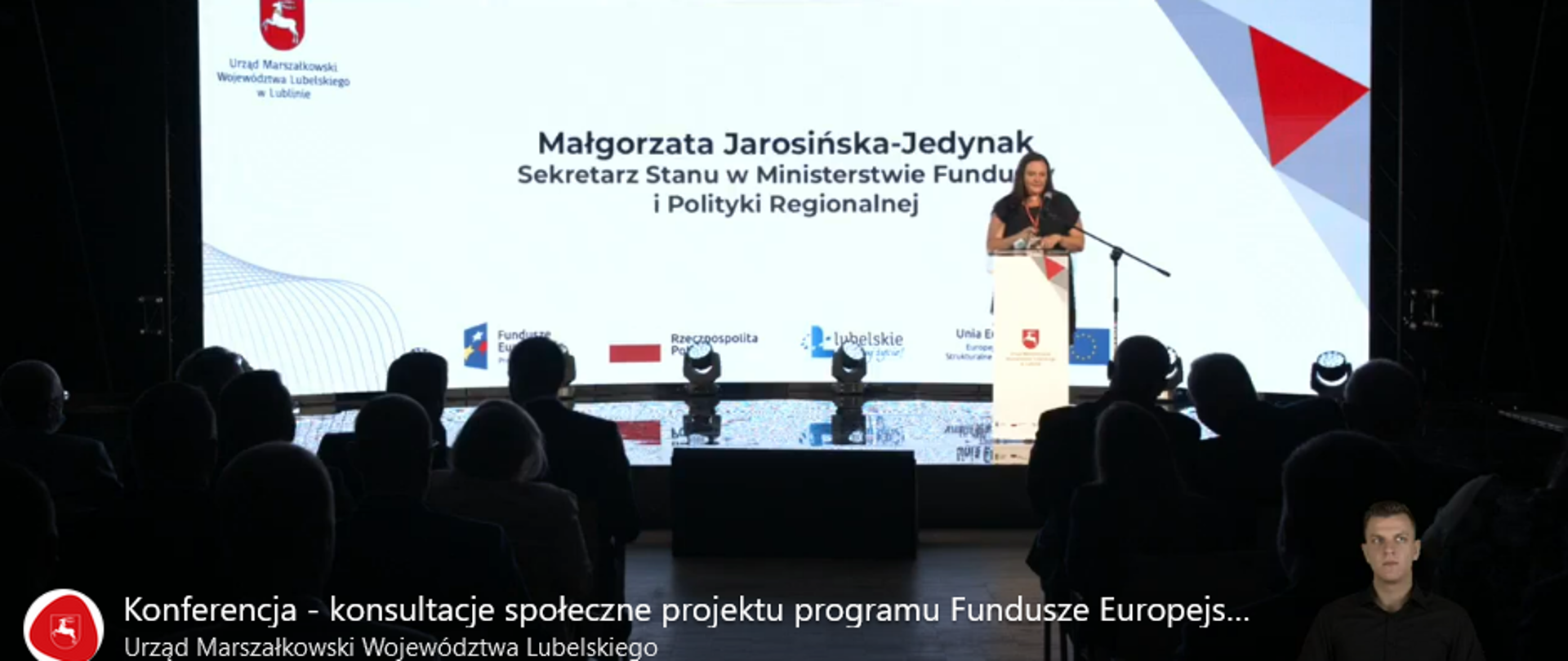 Na tle widowni na scenie w mównicy stoi wiceminister Małgorzata Jarosińska-Jedynak