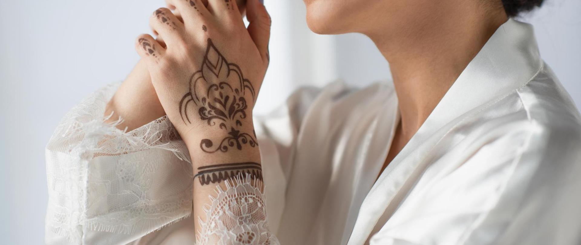 Na zdjęciu jest kobieta. W centrum uwagi jest jej dłoń z widocznym tatuażem z henny.