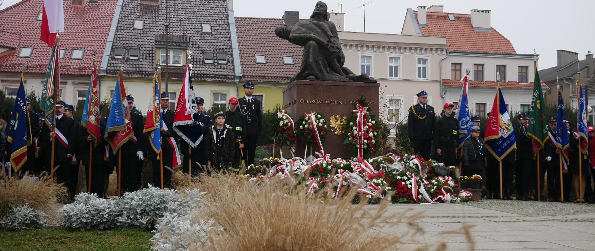 Na zdjęciu znajdują się poczty sztandarowe oraz inne osoby ustawione przy pomniku Śląskiej Piety, w tle wdać kamienice miasta