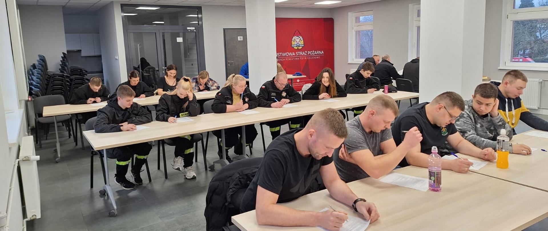Druhny i druhowie piszą egzamin teoretyczny na sali szkoleniowej w Komendzie Powiatowej Państwowej Straży Pożarnej w Człuchowie. 