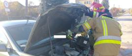 Strażacy odłączają źródło zasilania elektrycznego samochodu osobowego