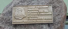 Mosiężna tablica pamiątkowa z tekstem: "Pamięci strażaków poległych w latach 1939-1945 w walce z faszyzmem o wolną i niepodległą Polskę"; "Pożarnicy województwa piotrkowskiego". Na lewej stronie tablicy widoczny hełm strażacki z orłem.
