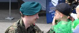 Żołnierz maluje dziecku barwy maskujące na twarzy