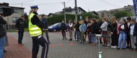 Policjantka uczy dzieci bezpiecznych zachowań podczas jazdy na hulajnodze