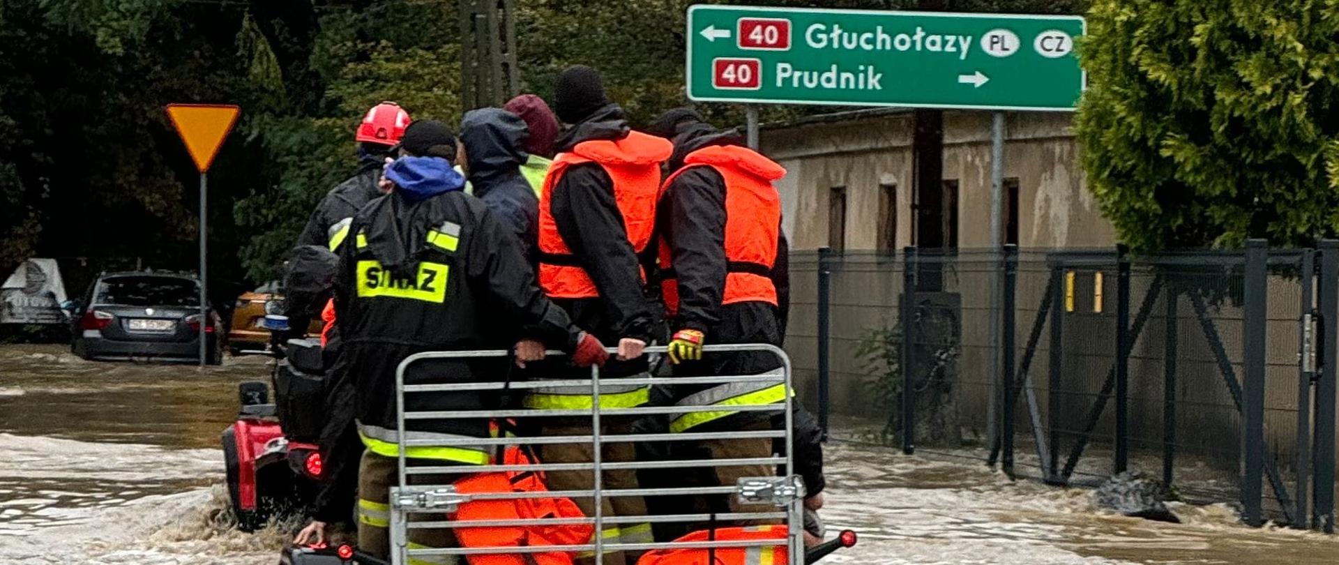 Strażacy przemieszczają się po terenach zalanych na przyczepie 