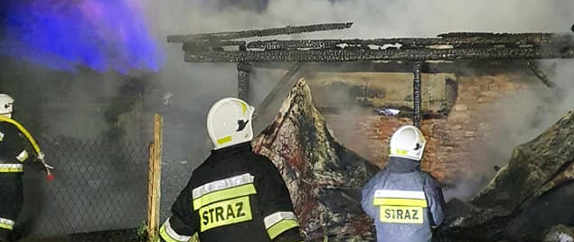 Na zdjęciu strażacy OSP ze sprzętem burzącym i linią gaśniczą naprzeciwko pożaru budynków gospodarczych w trzemosznie