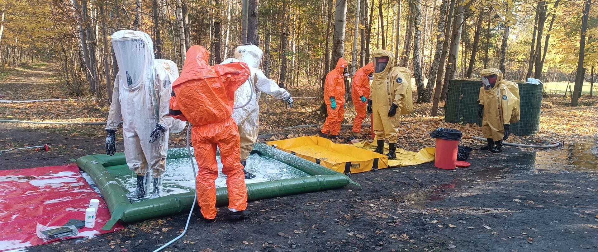 Strażacy w ubraniach chemicznych podczas procesu dekontaminacji