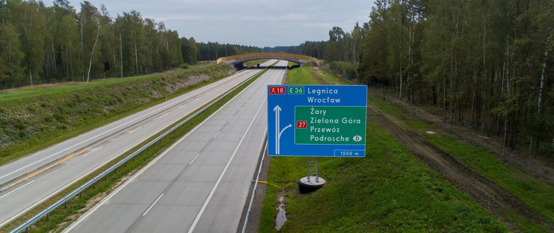 Autostrada A18 z widoczną na pierwszym planie tablicą kierunkową (Legnica, Wrocław), na dalszym planie widoczne duże przejście dla zwierząt