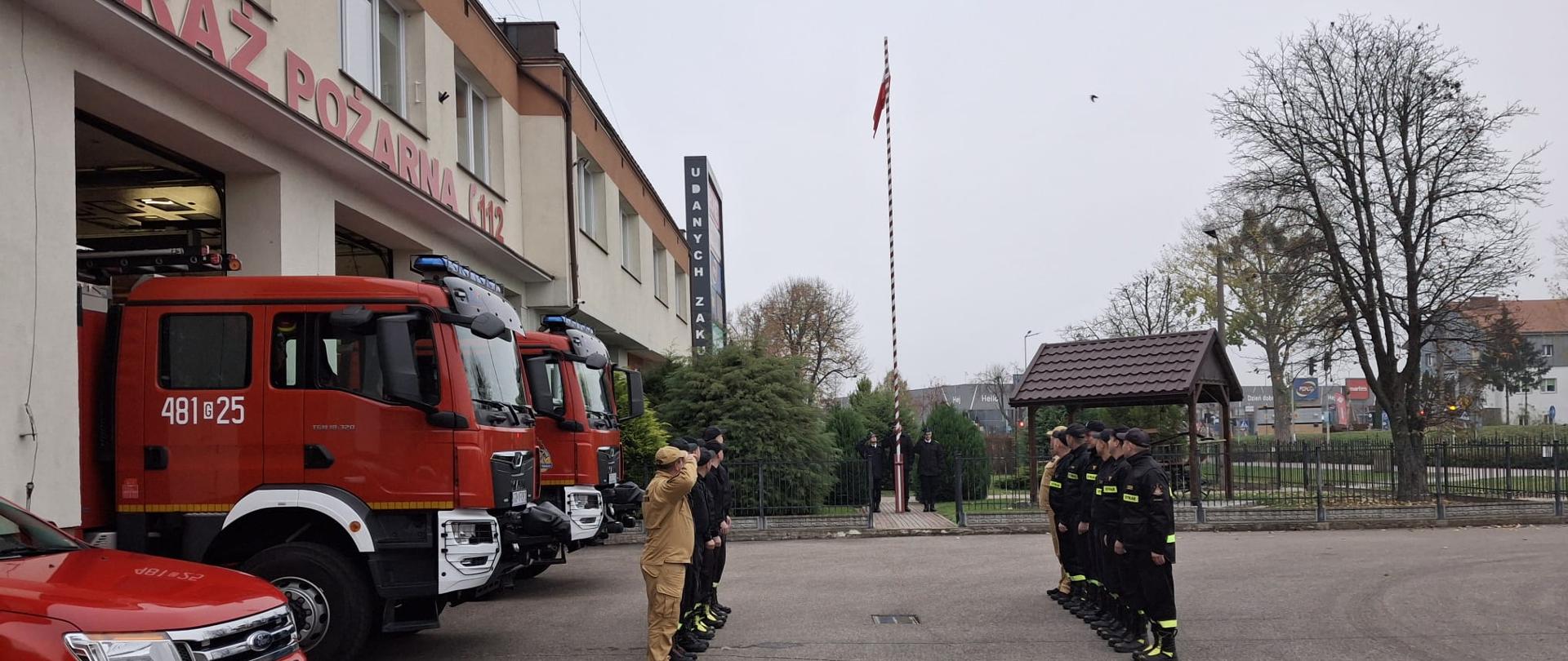 Strażacy na uroczystej zmianie służby podnoszą Flagę Państwową