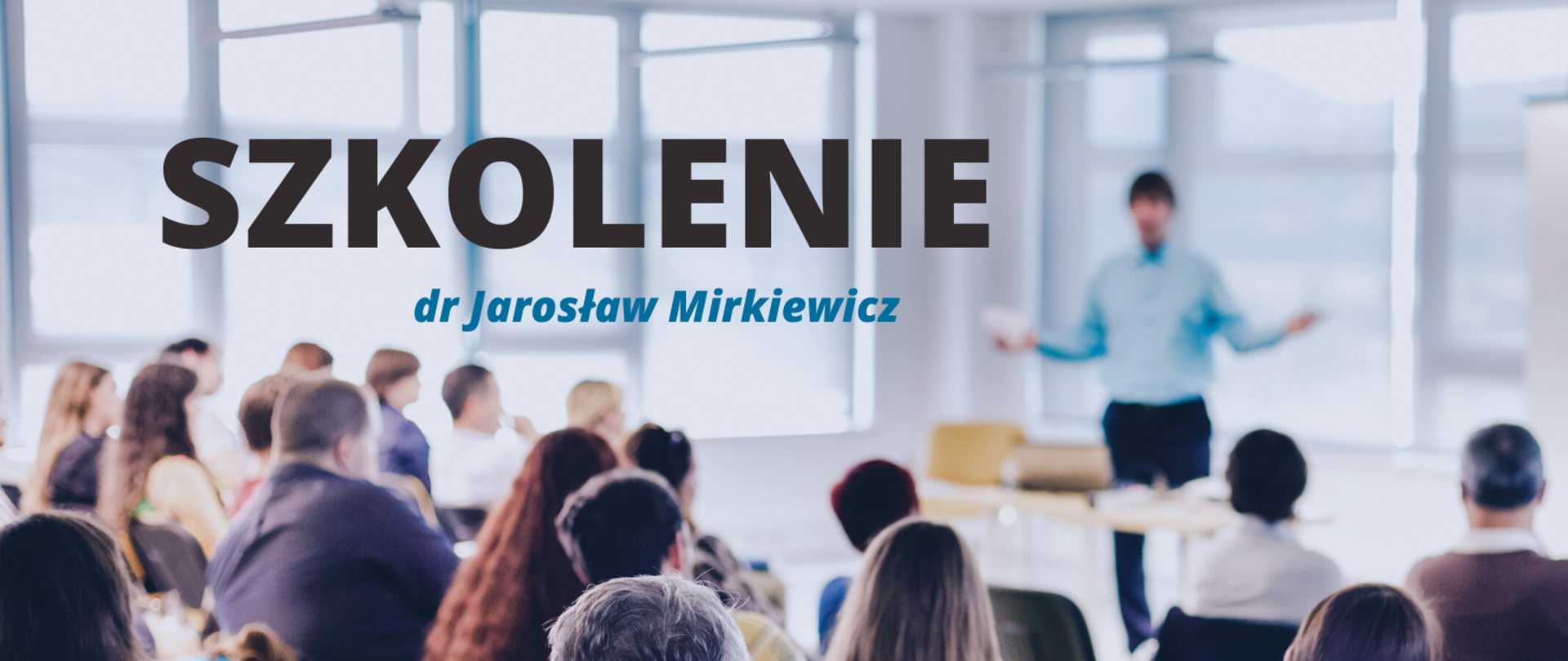 Baner z czarnym napisem "SZKOLENIE" i niebieskim "dr Jarosław Mirkiewicz". W tle zdjęcie wykładowcy w niebieskiej koszuli, rozkładającego ręce przed którym siedzą uczestnicy wykładu. Zdjęcie w delikatnym rozmyciu.