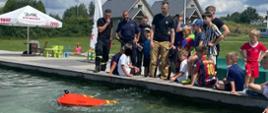 Strażacy prezentują młodzieży inteligentne koło ratunkowe na basenie zewnętrznym