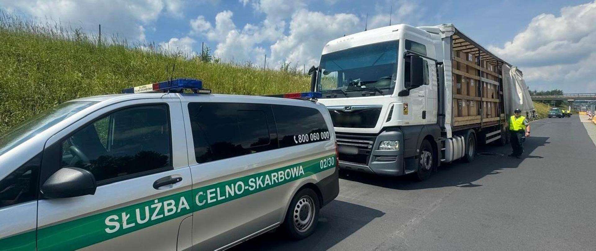 Radiowóz Służby Celno-Skarbowej, zatrzymany samochód ciężarowy, funkcjonariusz przy naczepie.