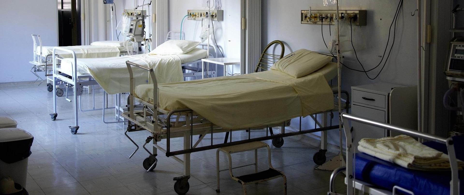 Sala szpitalna z trzema pustymi łóżkami