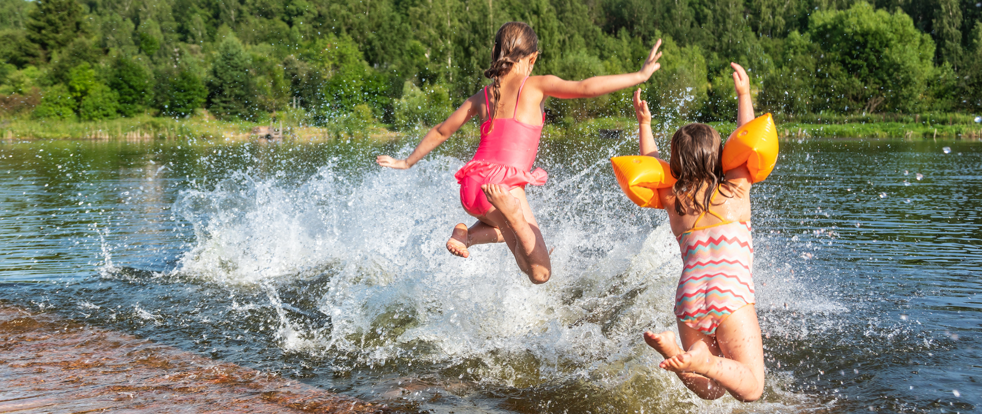 dwie dziewczynki skaczą z pomostu do jeziora
