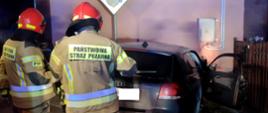 Zdjęcie przedstawia strażaków prowadzących działania ratownicze w obrębie wraku pojazdu Audi.