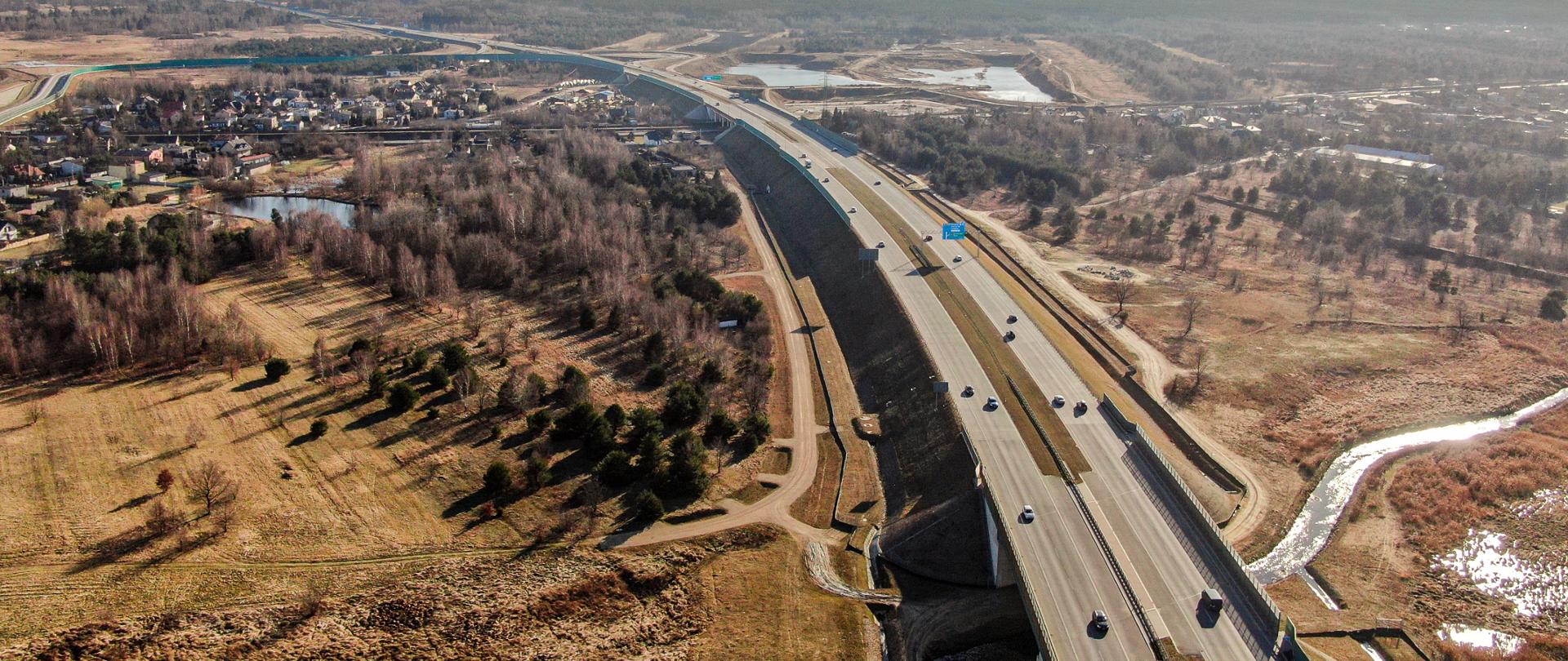 Widok z lotu ptaka na autostradę A1. Po bokach widoczne drzewa i zabudowania. Dzień, pogoda jesienna.