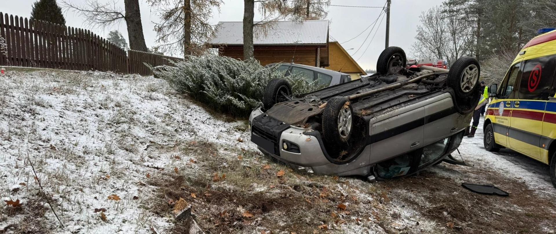 na poboczu drogi na dachu leży samochód fiat panda, w tle pojazdy służb