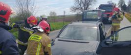 Strażacy otwierają maskę samochodu osobowego