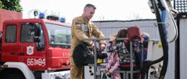 Strażak prezentuje dzieciom jak operować podnośnikiem hydraulicznym