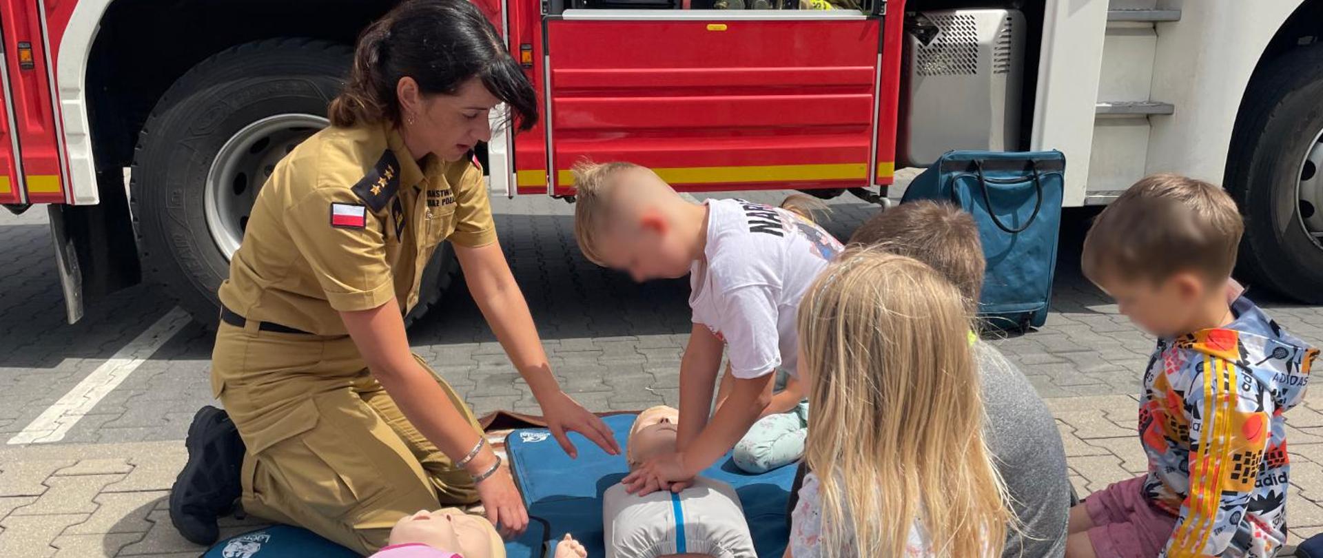 Na zdjęciu Pani strażak uczy dzieci pierwszej pomocy