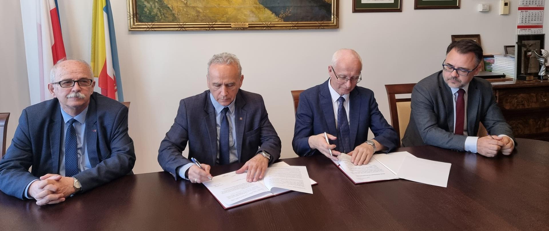 Podpisanie umowy o współpracy - czterej przedstawiciele Politechniki i GDDKiA przy stole konferencyjnym - dwaj podpisują egzemplarze umowy 