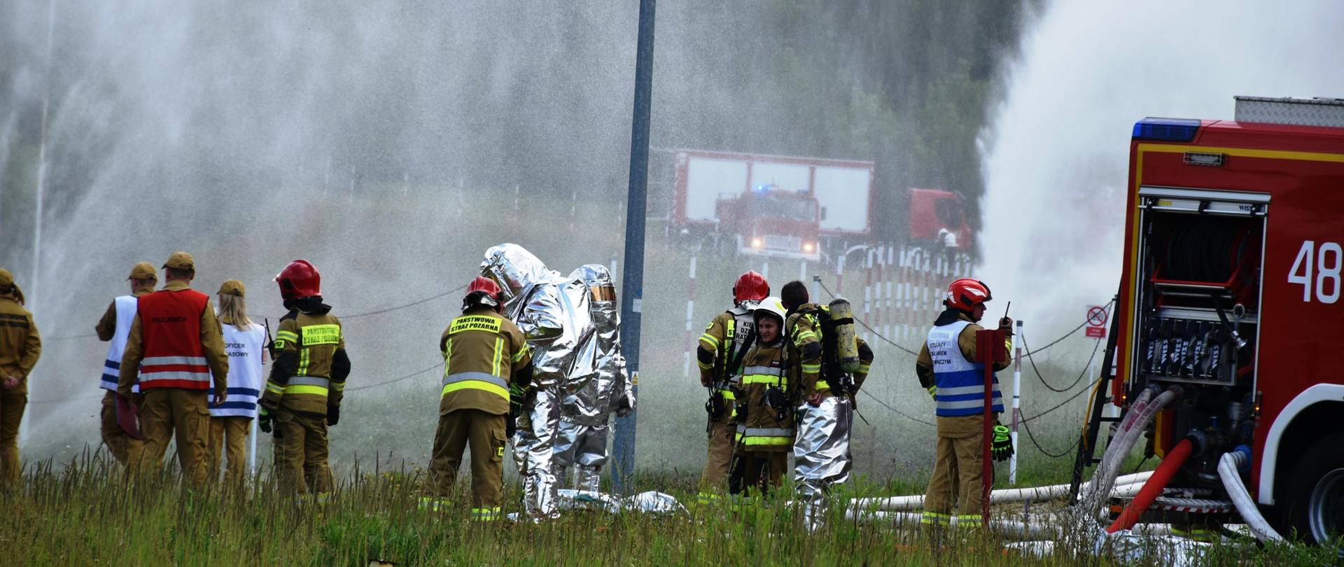 Widok na ubierających się strażaków w ubrania żaroochronne i pracę strażaków w ochronie przed oddziaływaniem termicznym.