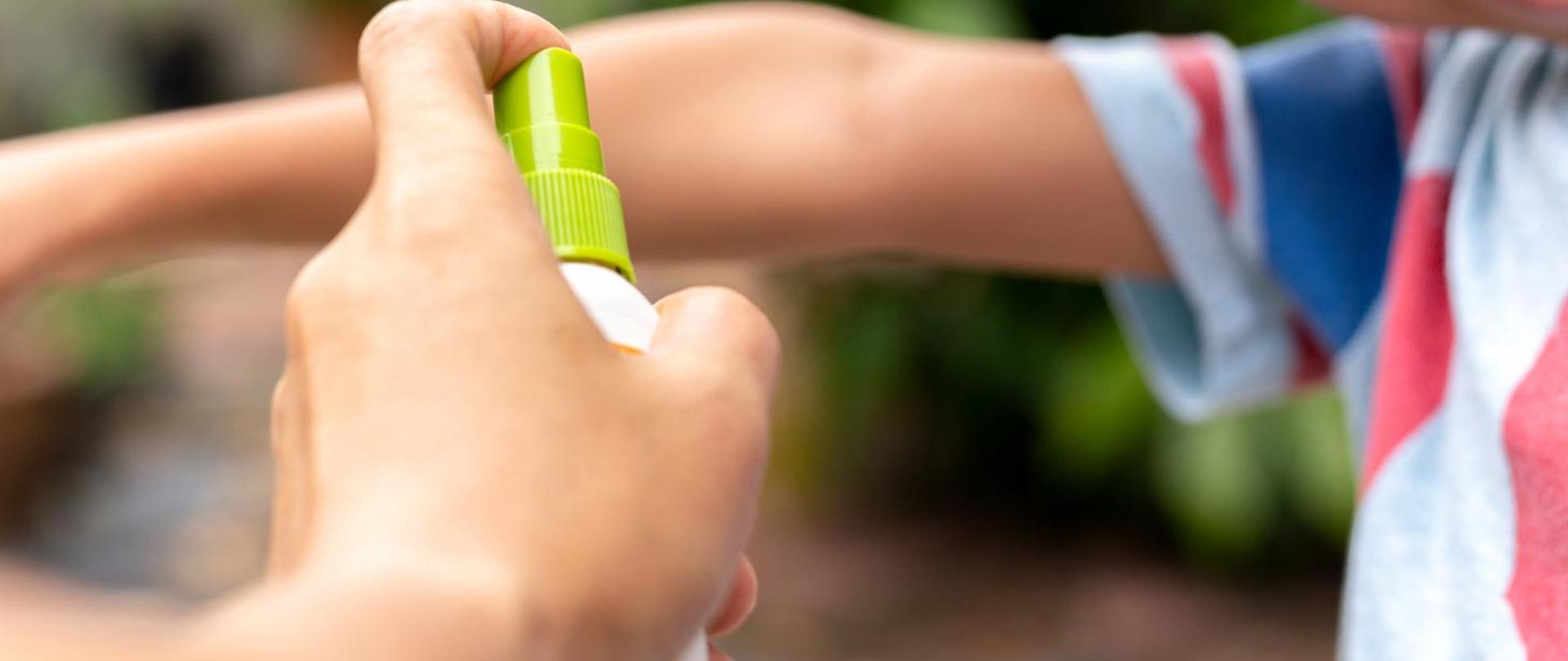 Father spraying insect repellents on his son arm in the garden