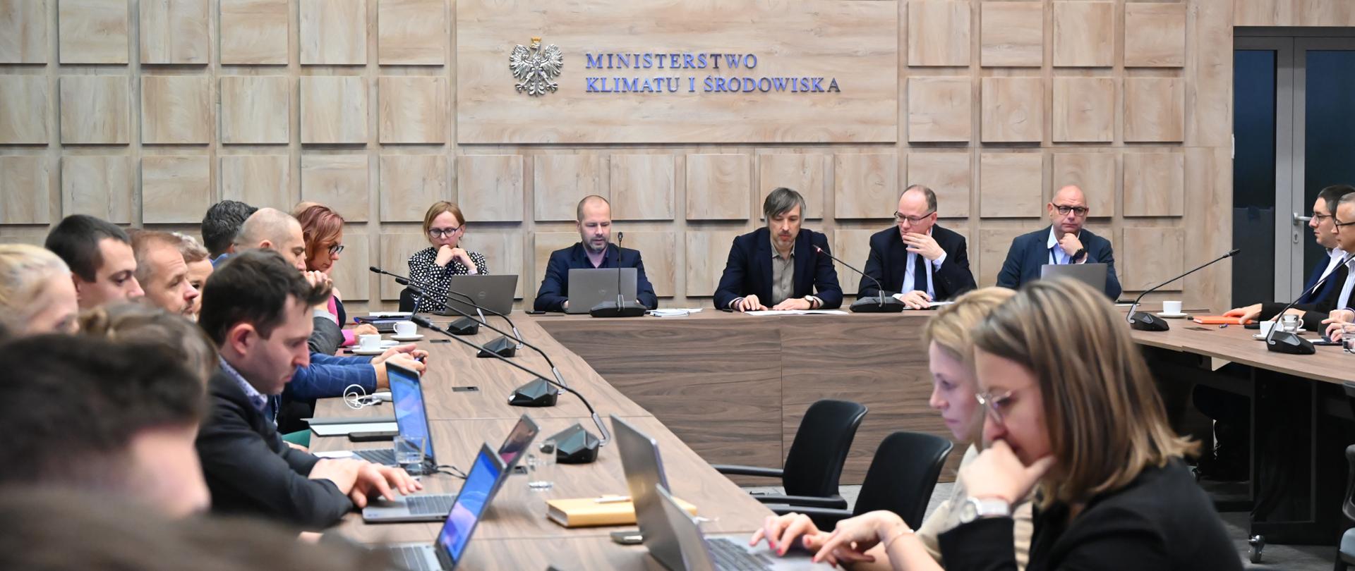 Uczestnicy spotkania. W tle widać drewniane dekoracje ścienne i logotyp ministerstwa.