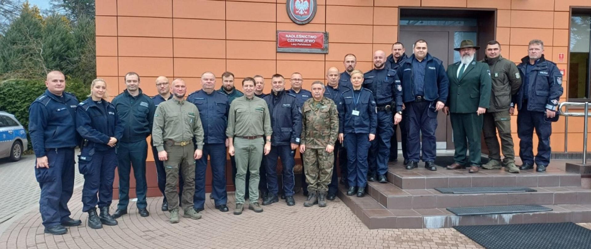 Zdjęcia pamiątkowe. Na tle budynku Nadleśnictwa Czerniejewo stojący obok siebie wszyscy uczestnicy spotkania