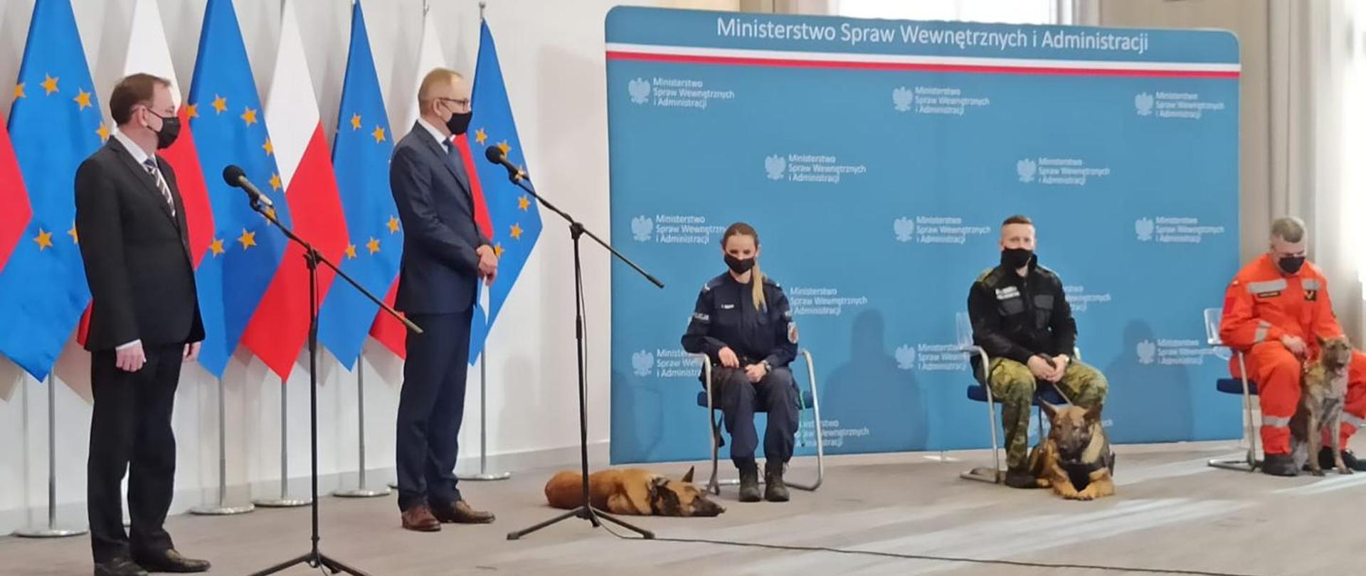 Na zdjęciu Minister Spraw Wewnętrznych i Administracji oraz funkcjonariusze służb mundurowych i ich psy podczas konferencji