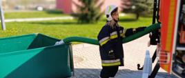 Strażak - ratownik z jednostki Ochotniczej Straży Pożarnej podczas obsługi autopompy samochodu pożarniczego .
