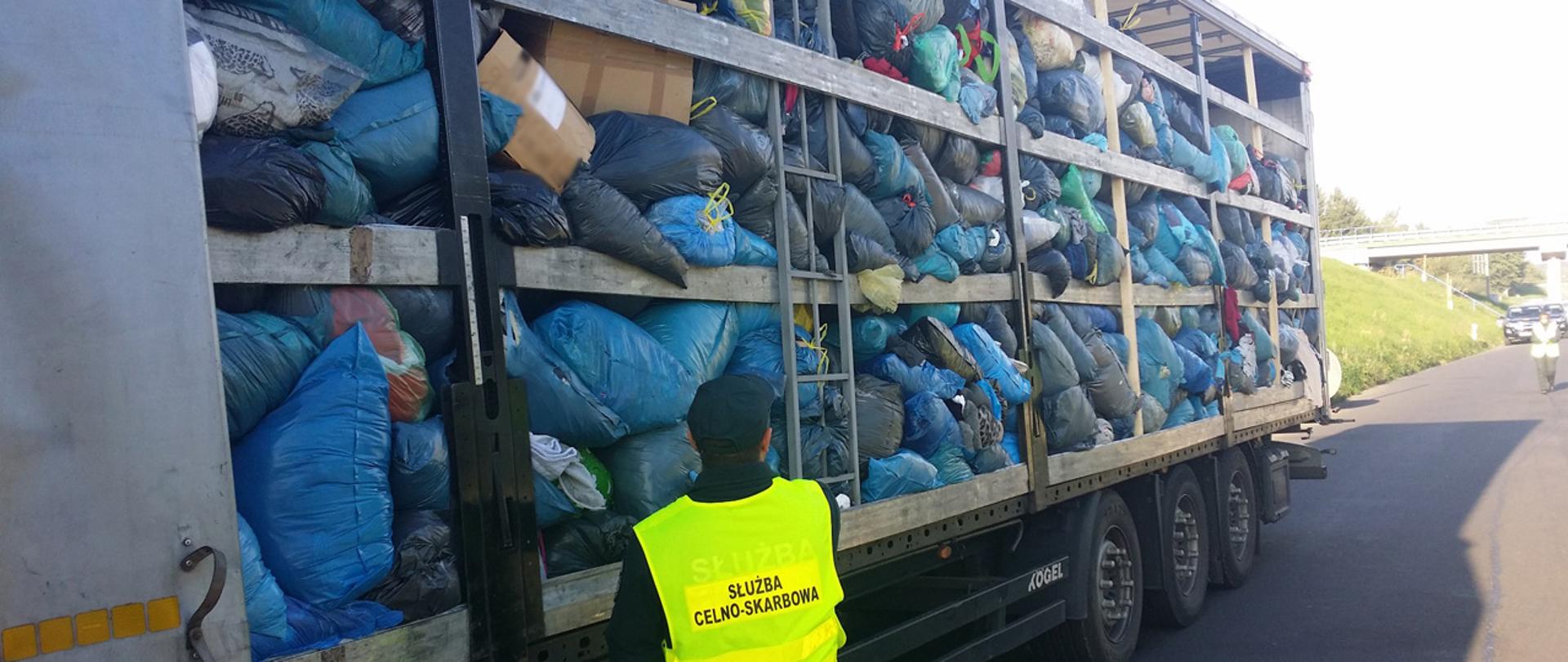 Funkcjonariusz Służby Celno-Skarbowej przy naczepie samochodu ciężarowego, naczepa załadowana jest workami z odpadami.