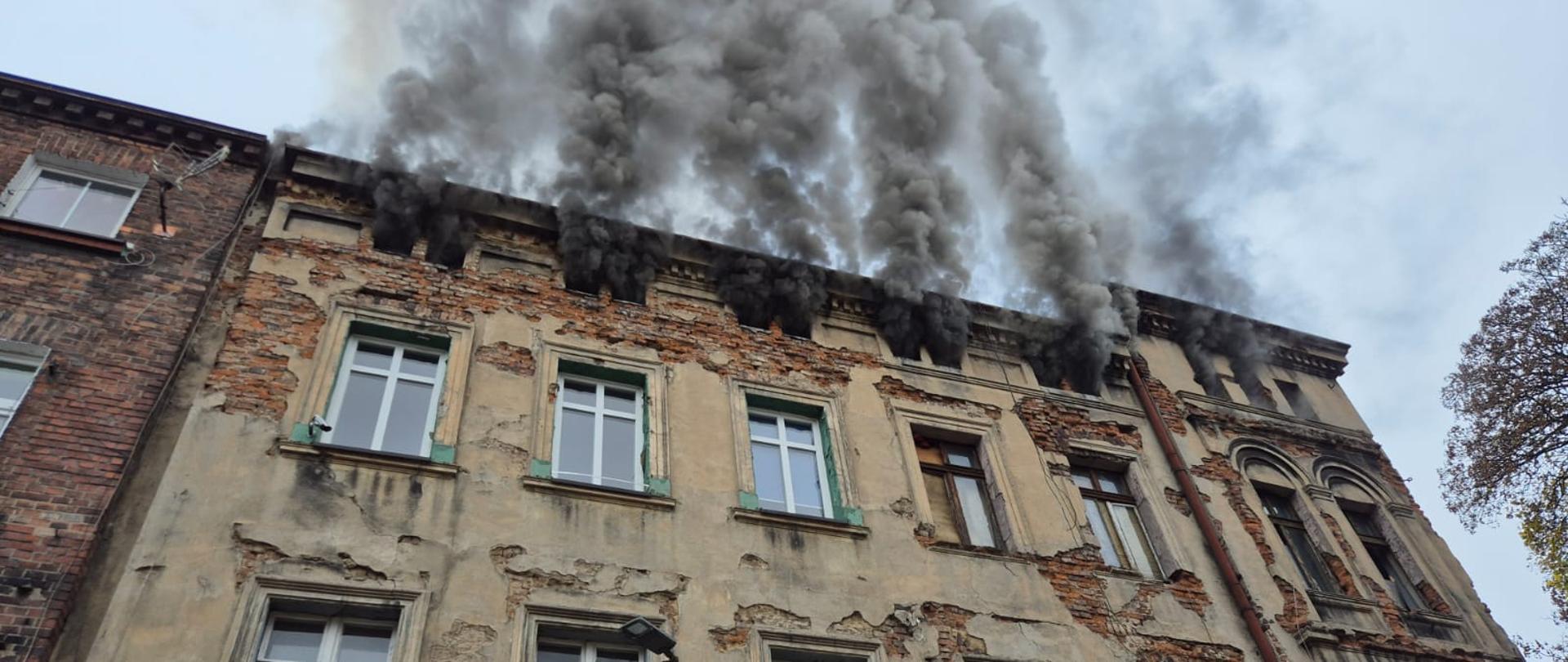 Na zdjęciu widoczny budynek. Z okien na ostatniej kondygnacji wydobywa się dym.