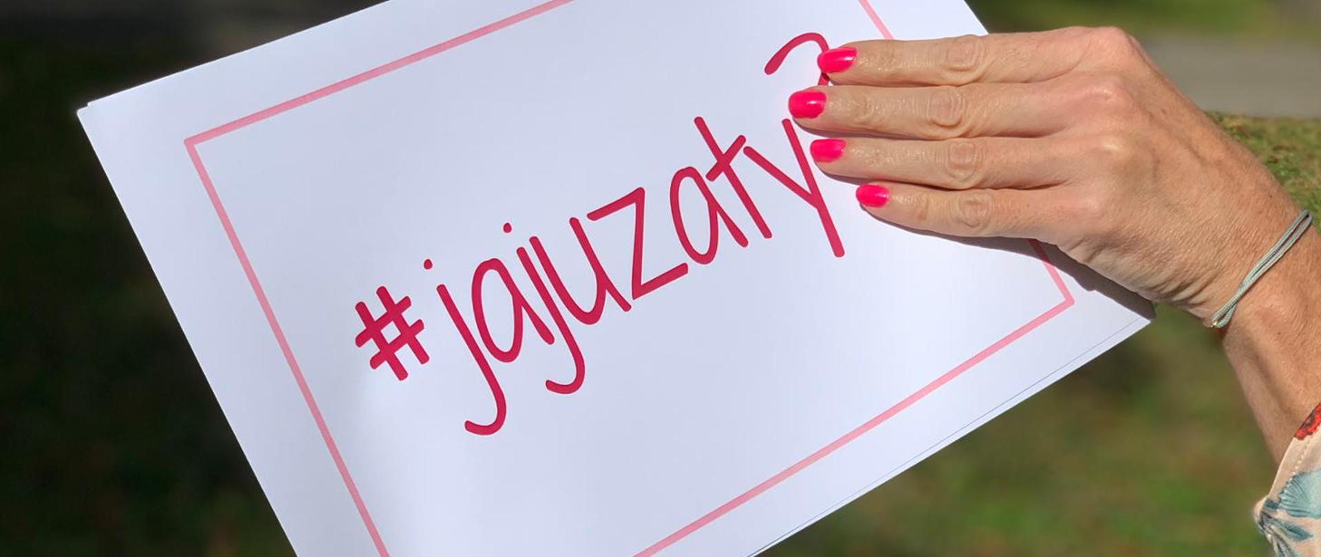 Kobieca dłoń trzyma białą kartkę z napisem #jajuzaty?