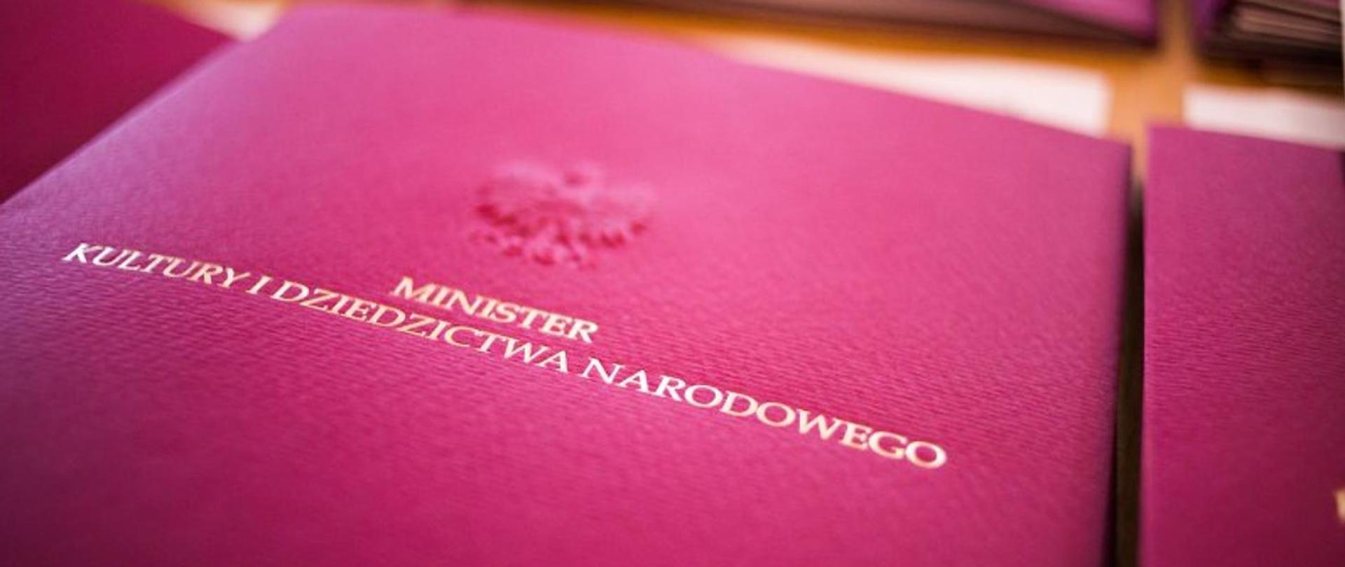 Bordowa teczka z napisem Minister Kultury i Dziedzictwa Narodowego i logiem orła.