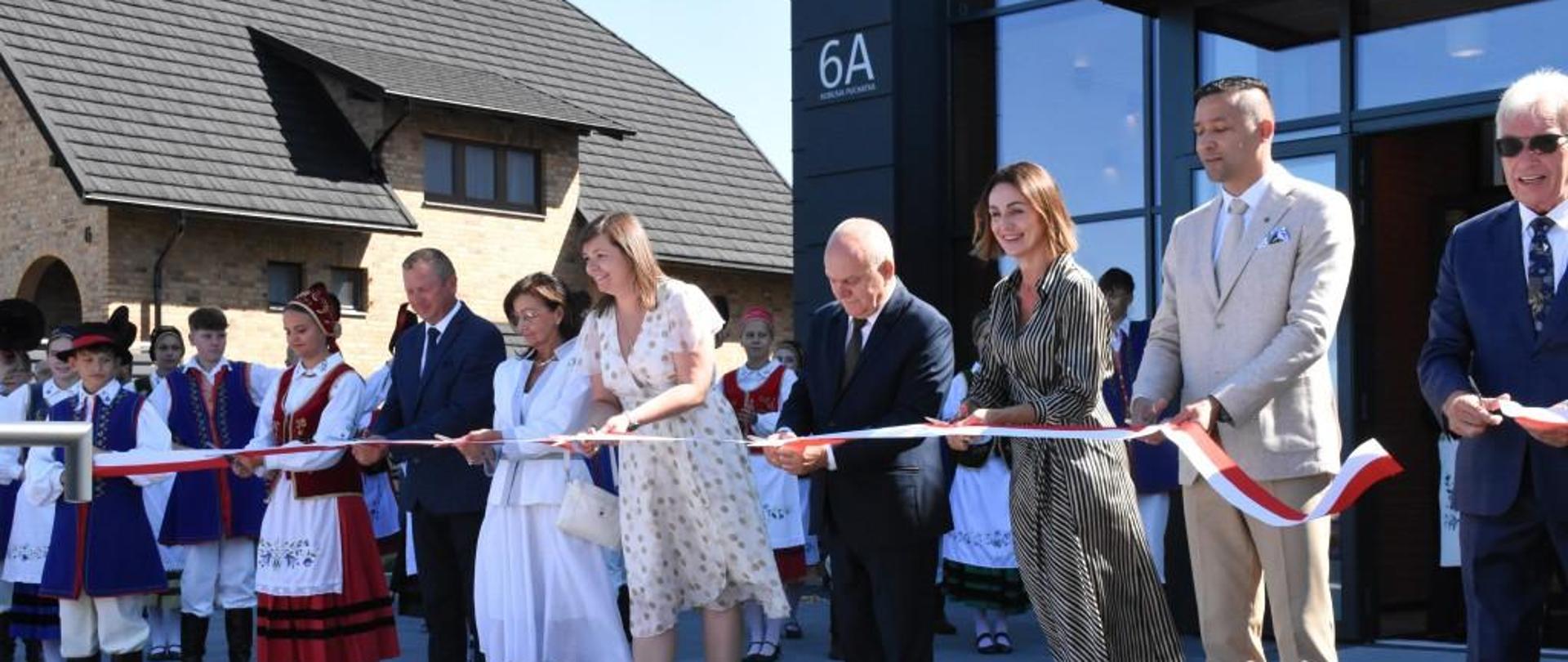 Na zdjęciu widnieje grupa ludzi, która przecina wstęgę, otwierając tym samym nowe Centrum Kultury w Sierakowicach.