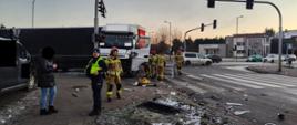 Uszkodzony pojazd mercedes z naczepą przy sygnalizatorze, w pobliżu strażacy