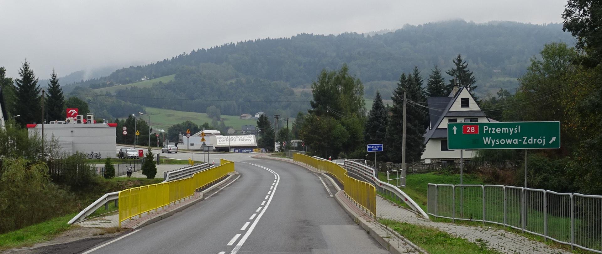 DK28, w tle Beskidy, na pierwszym planie most i znak na Przemyśl i Wysową-Zdrój, za mostem stacja paliw