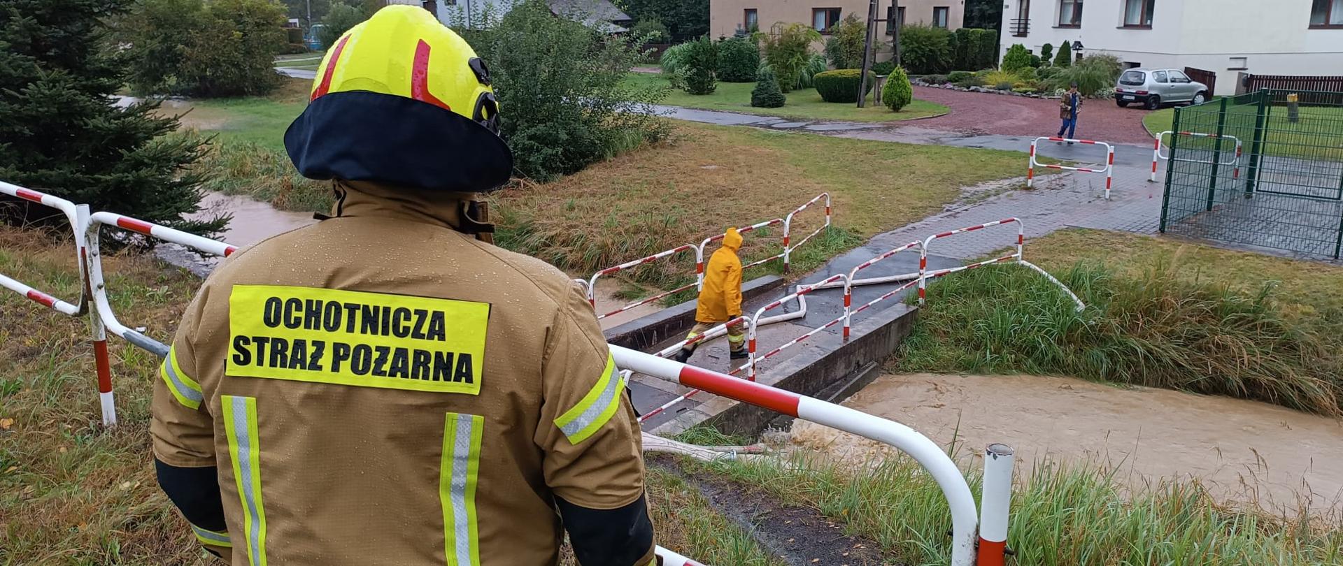 Strażak stoi nad rzeką i monitoruje jej stan